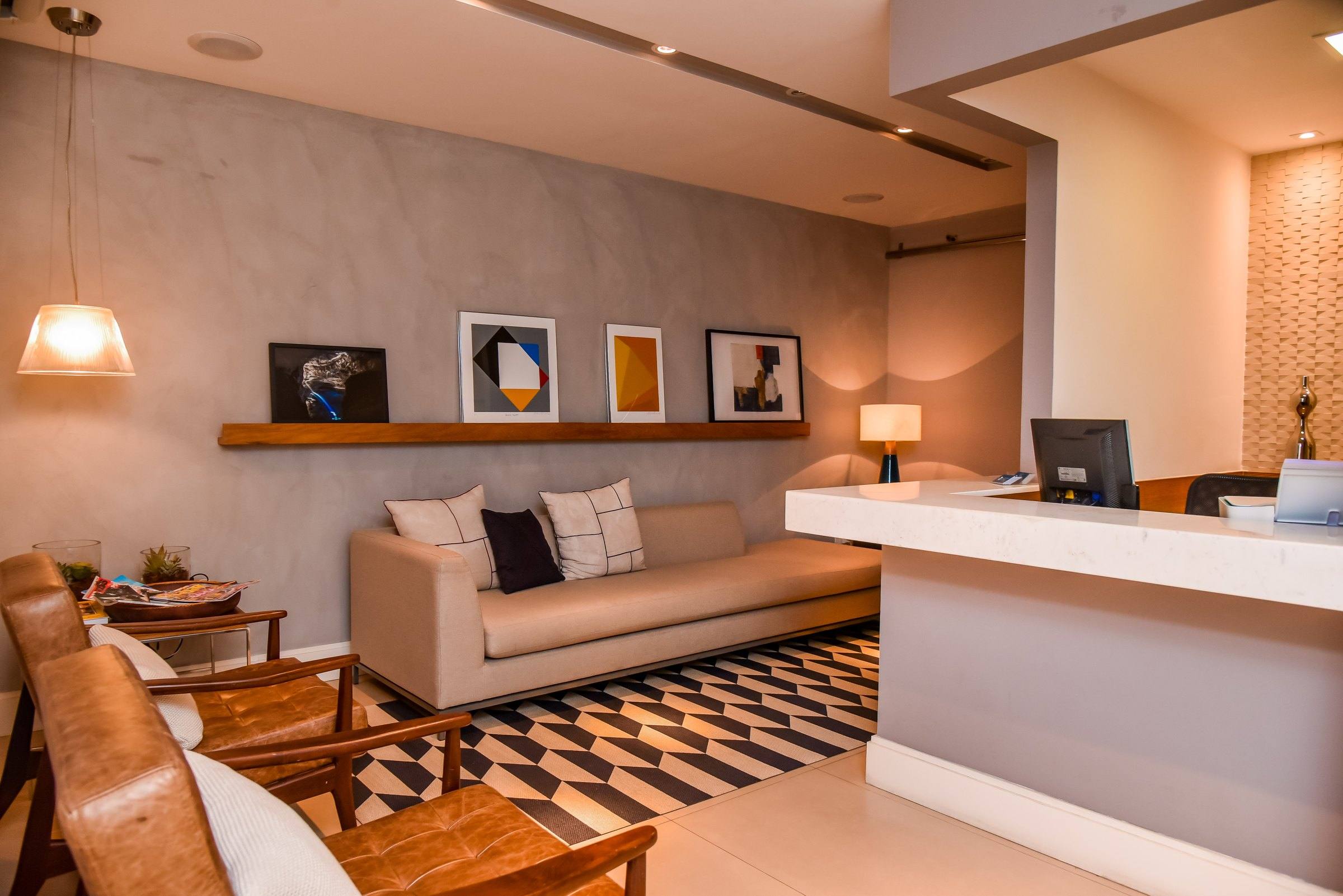 Sala de espera da clínica, com sofá claro e quadros na parede